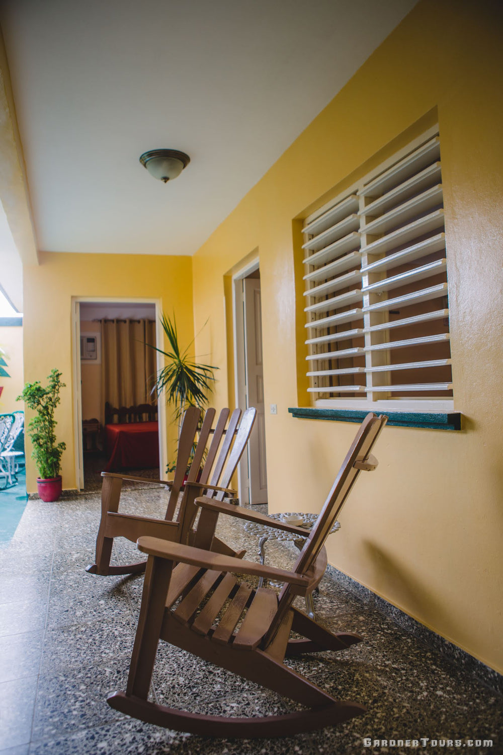 Gorgeous yellow and brown downstairs covered Porch Area with rocking chairs at a 3-star BnB in Vinales Cuba