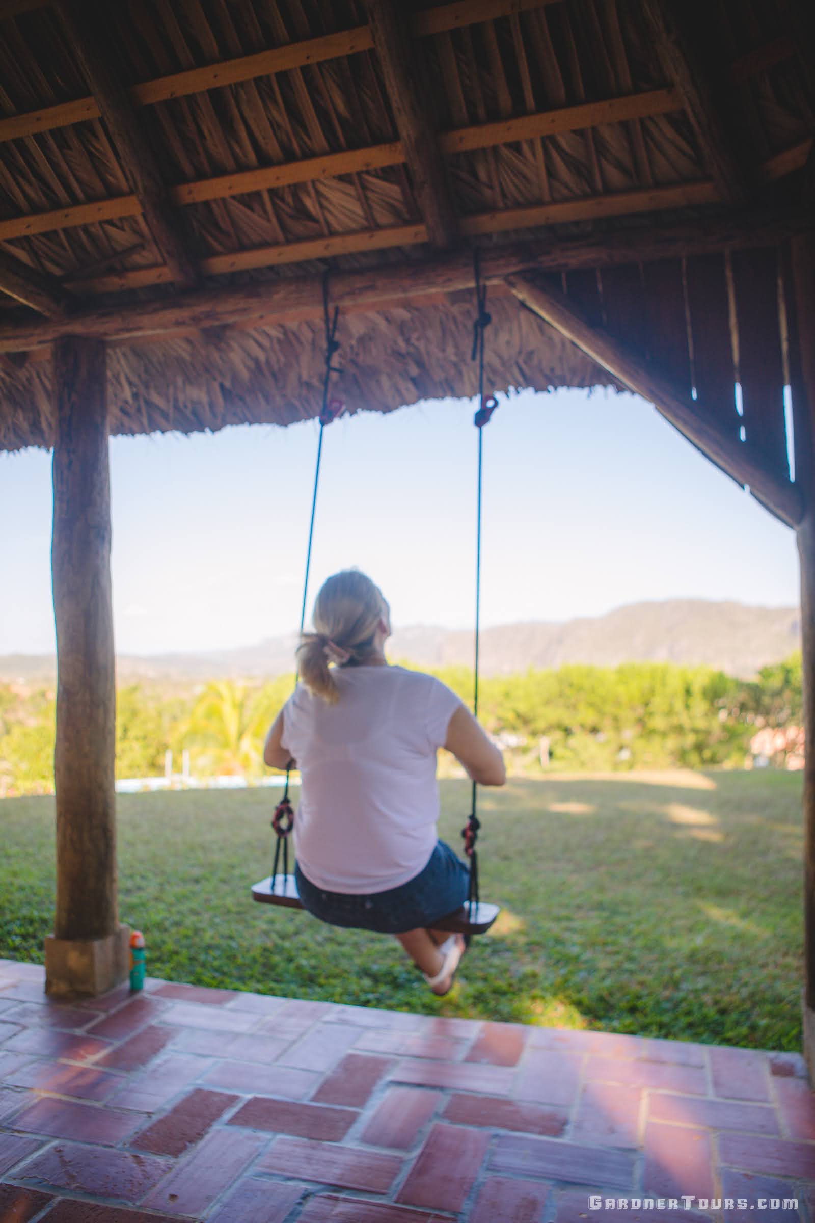 Photo of a woman swinging as she looks out over the Vinales Valley from her 4-star Casa Particular BnB in Viñales, Cuba