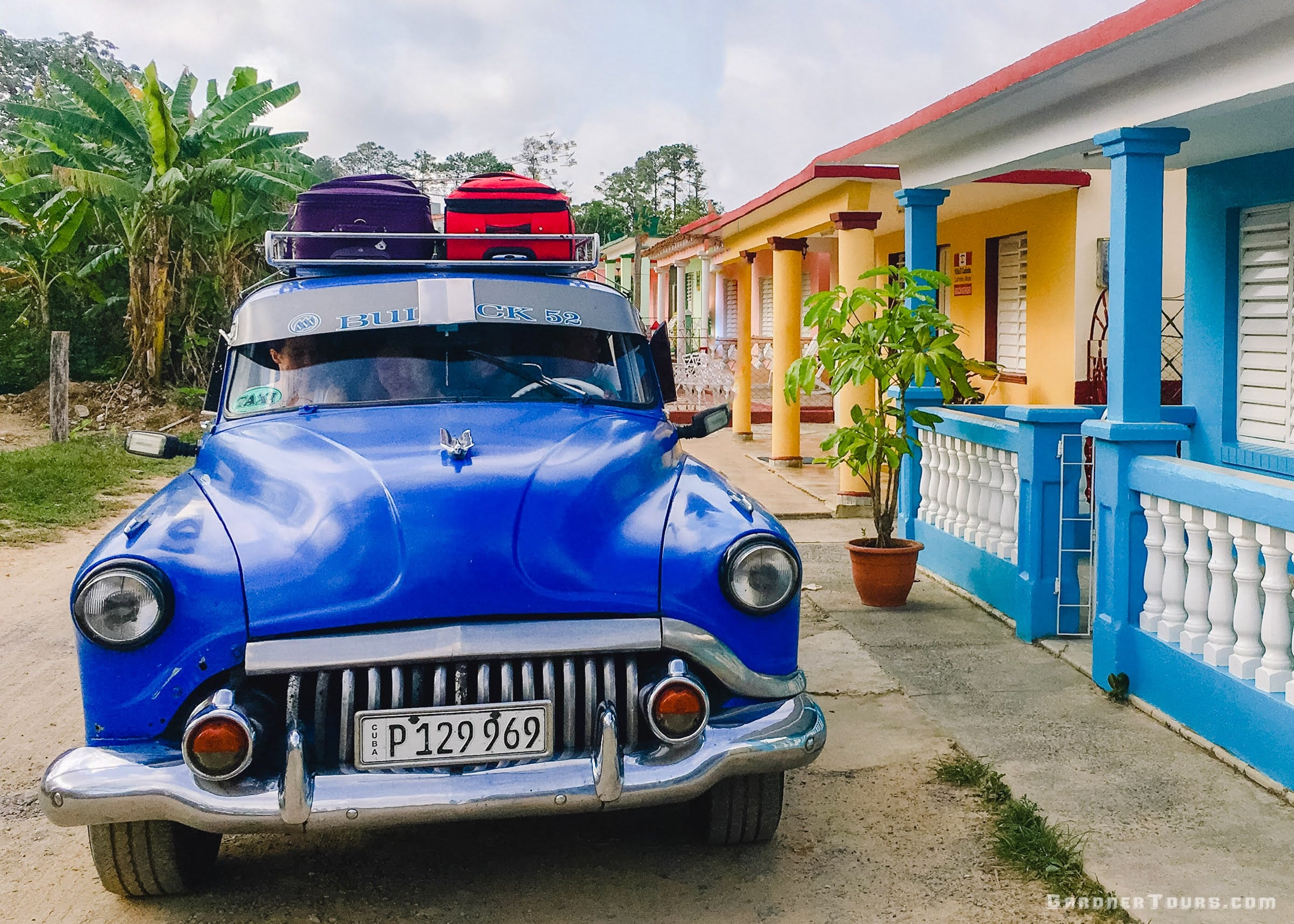Gardner Tours Blue Buick Classic Car with Luggage on Top sitting outside of BnB in Vinales Cuba
