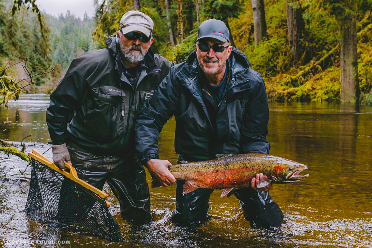 Two fishermen holding a large freshly caught salmon in a remote Southeast Alaska river.