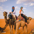 Couple experiencing a private camel trek through the Sahara Desert as part of Gardner Tours’ premier Best of Morocco Tour.