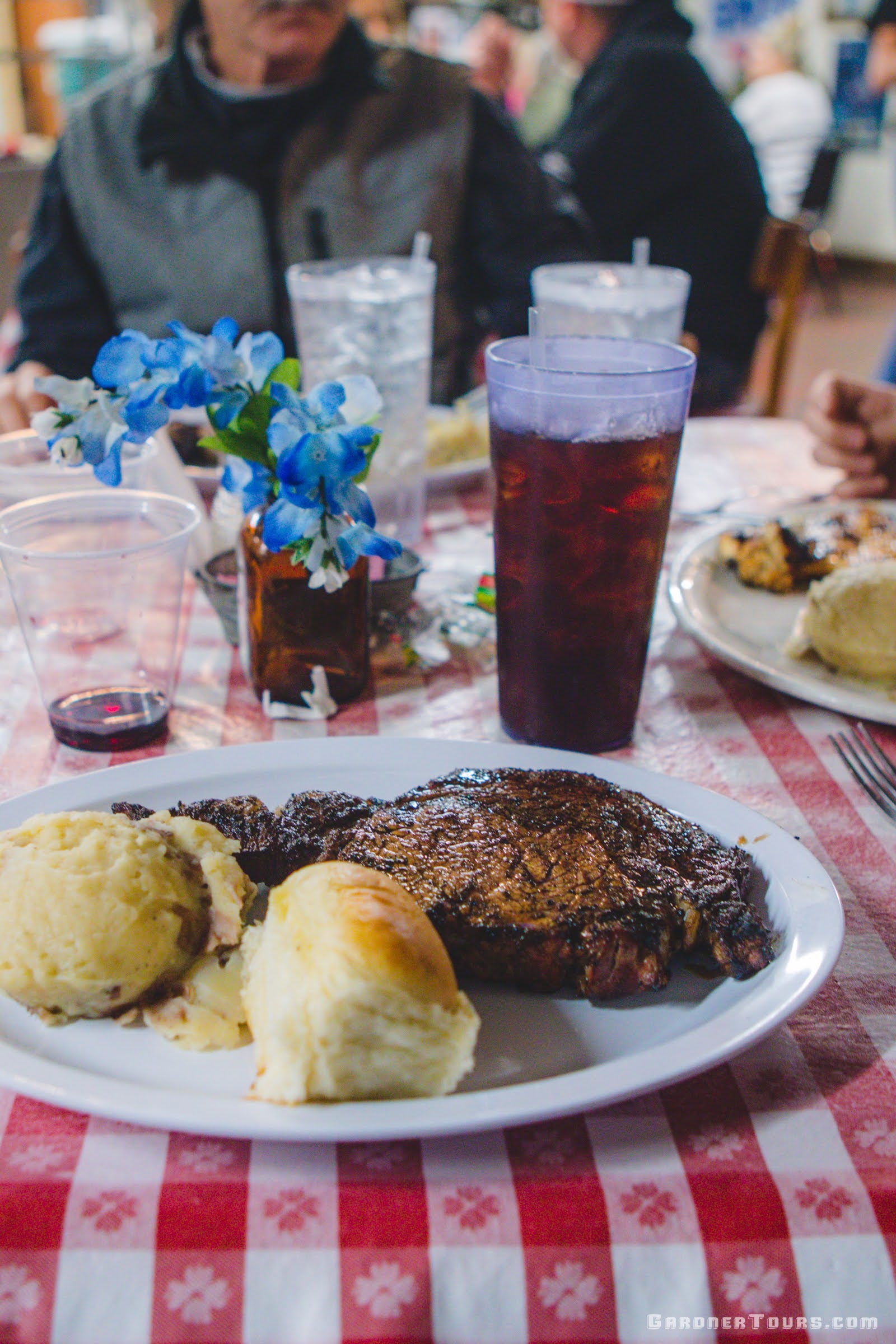 Close-up of a large steak plate on a table with a checkered table cloth at the Leona General Store in Leona, Texas.