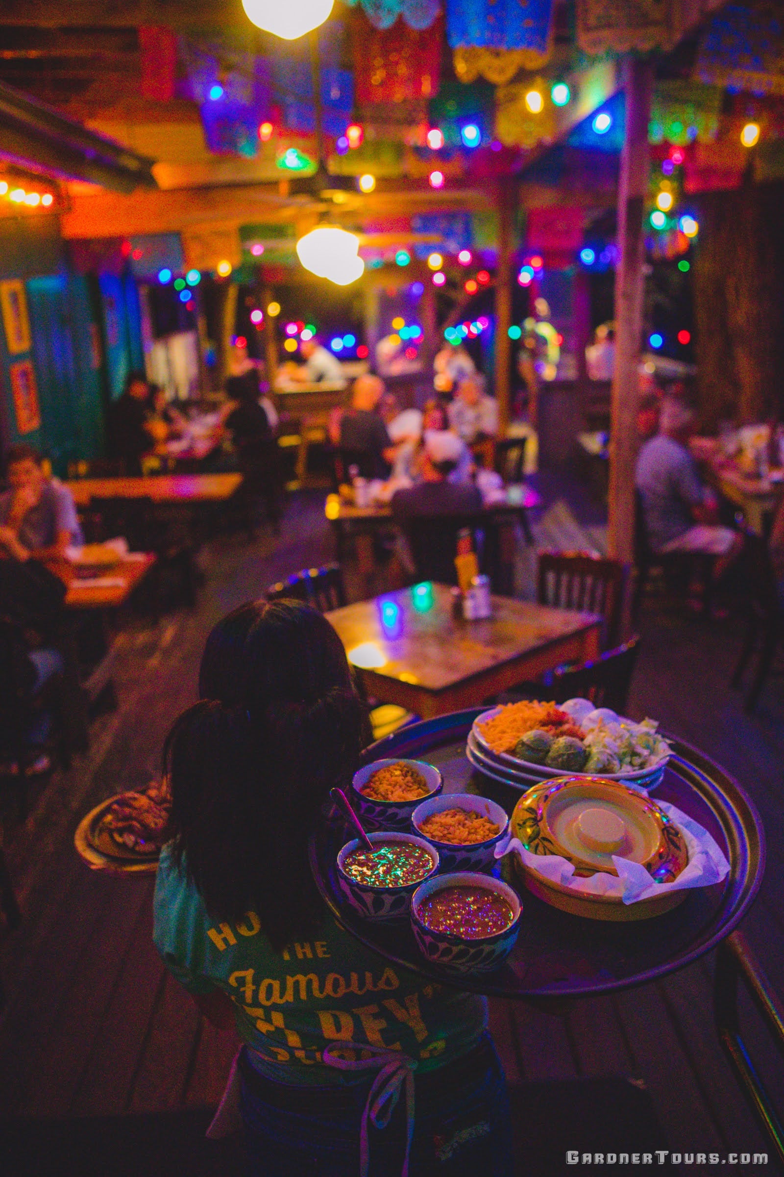Waitress carrying a large tray of food in a colorful Mexican restaurant in Gruene, Texas.