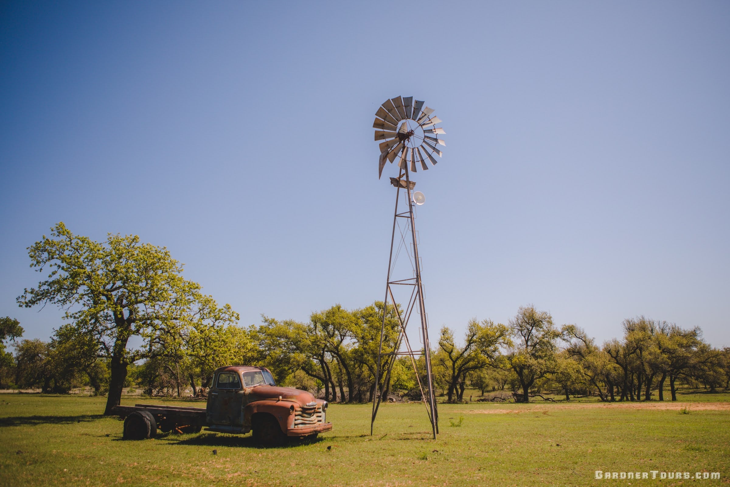 Rustic Classic Chevrolet 3100 pickup parked next to a windmill on a farm outside Fredericksburg, Texas.