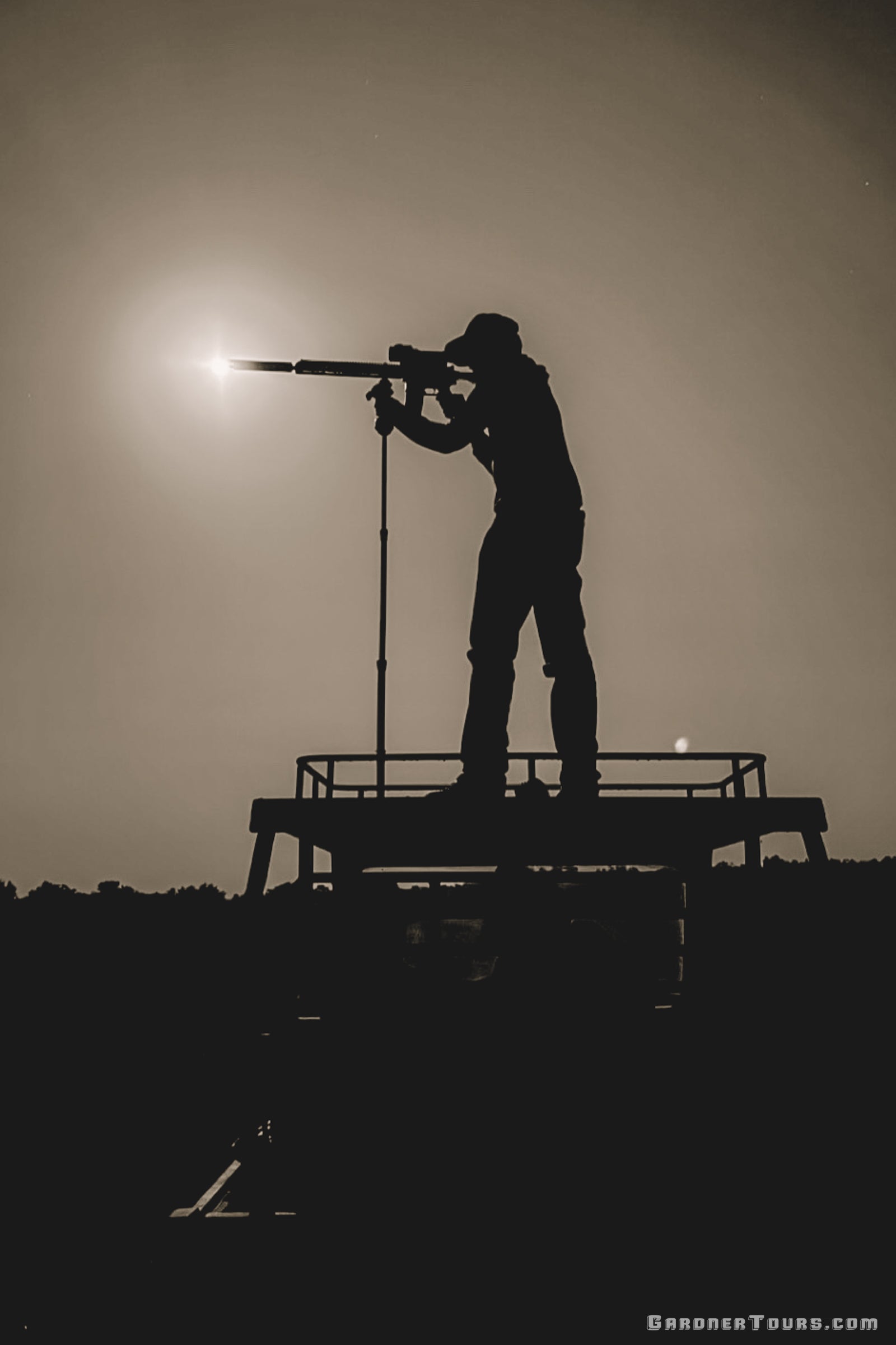 Silhouette of a hunter scanning for wild hogs from a high truck shooting platform during a night thermal hunt in Texas.