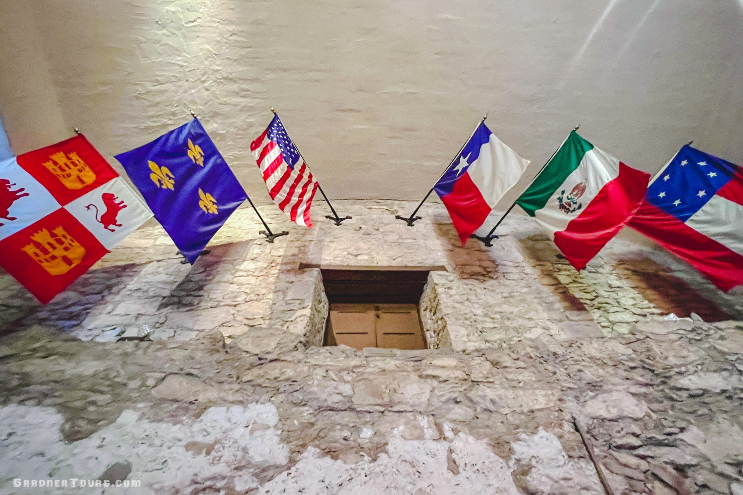 Six flags representing Texas history—Republic of Texas, Confederate States, United States, France, Spain, and Mexico—displayed inside the Alamo in San Antonio, Texas.