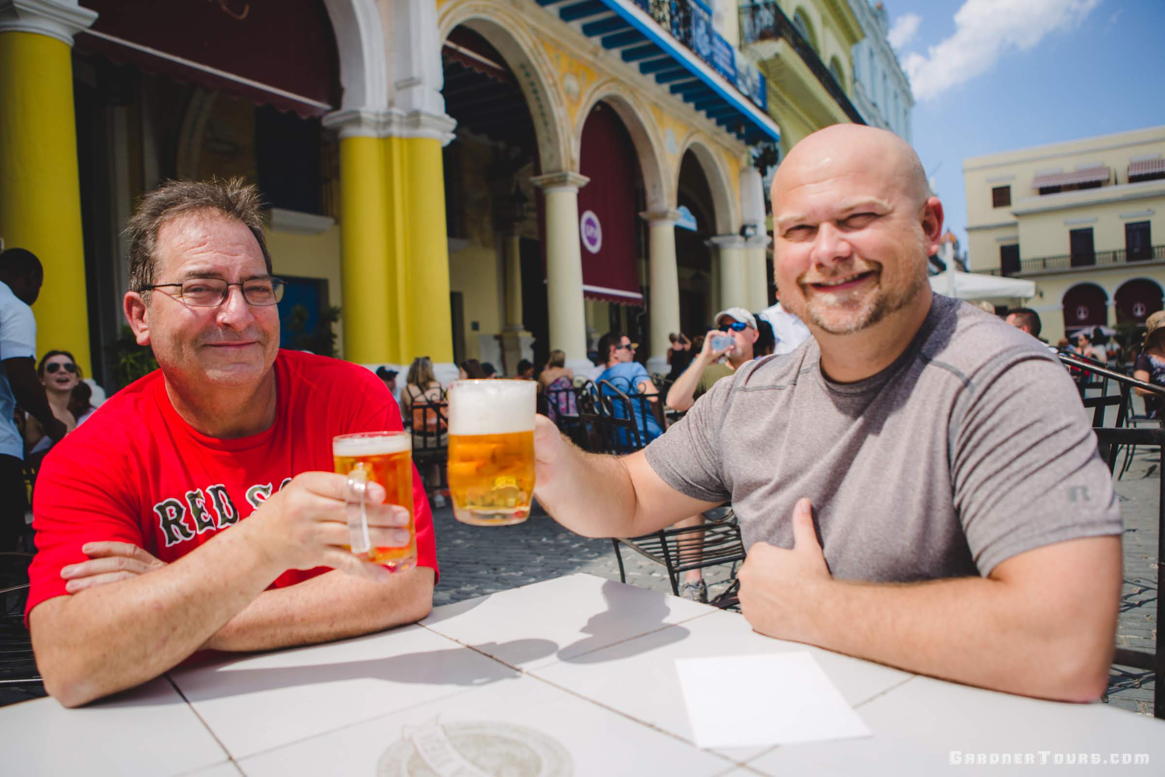 Two Men Sitting Outside Cheering To Their Successful Cuba Tour With Beer in Plaza Vieja Old Havana Cuba