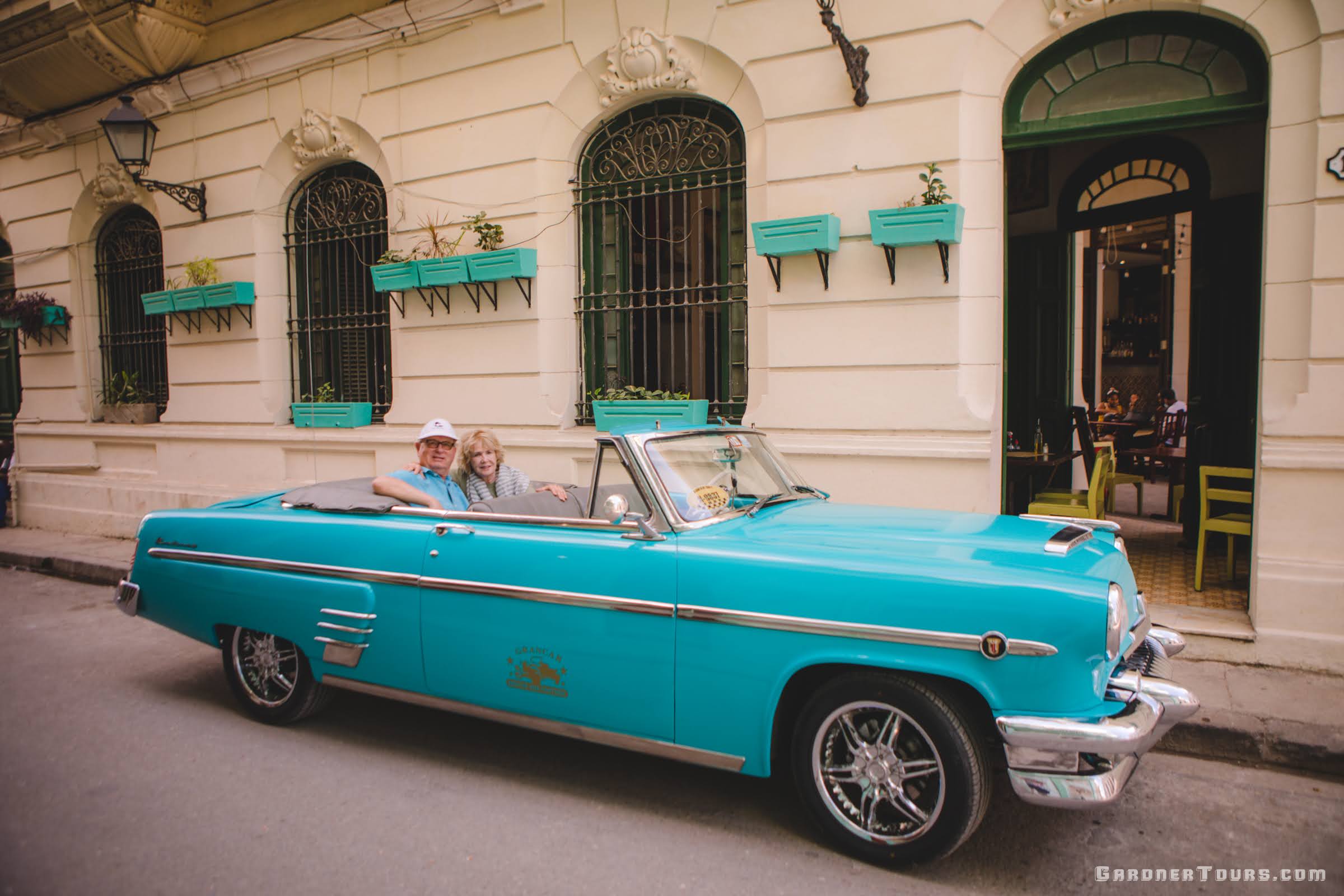 Elderly Couple Riding in Turquoise Buick Classic Car in 5 Esquinas Havana, Cuba