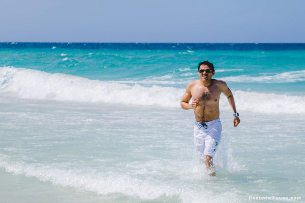 A handsome latino man runs Baywatch style in the water of the Playas del Este in Havana, Cuba