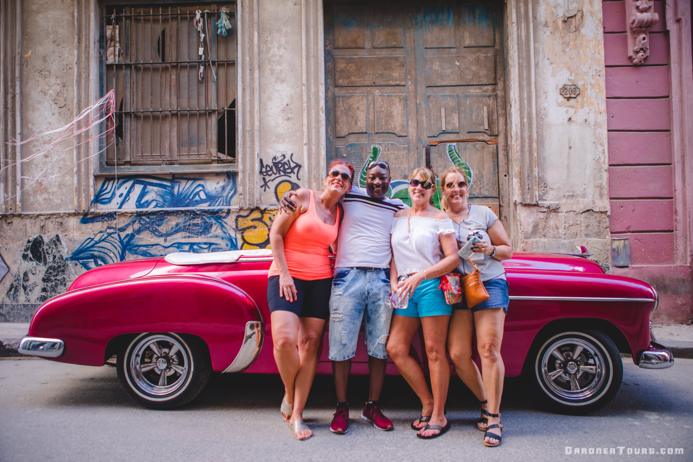 Four Friends Posing in front of Classic Car Tour Red Chevrolet Covertible