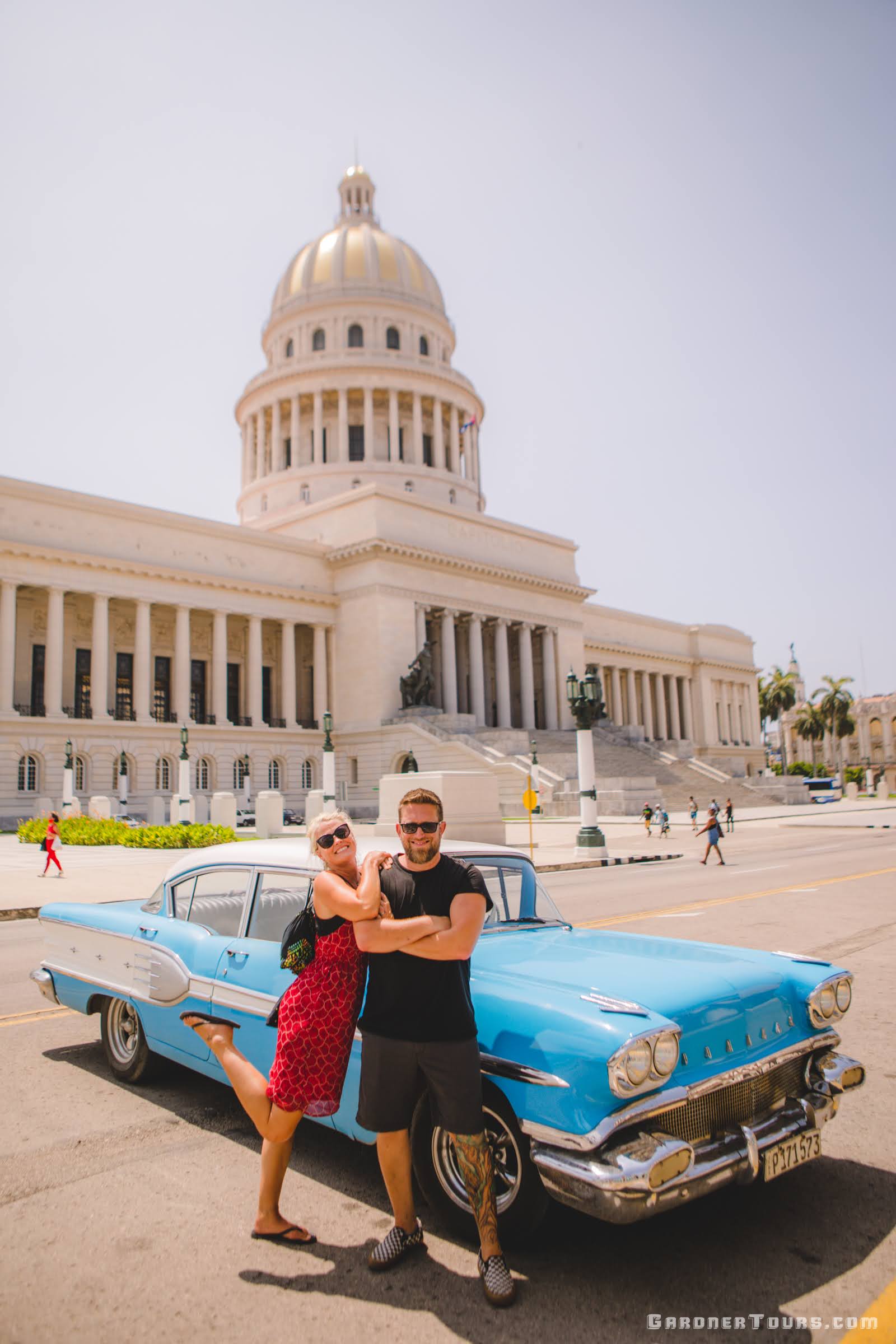 Couple with Blue Classic American Car in front of Cuban Capitol in Havana Cuba