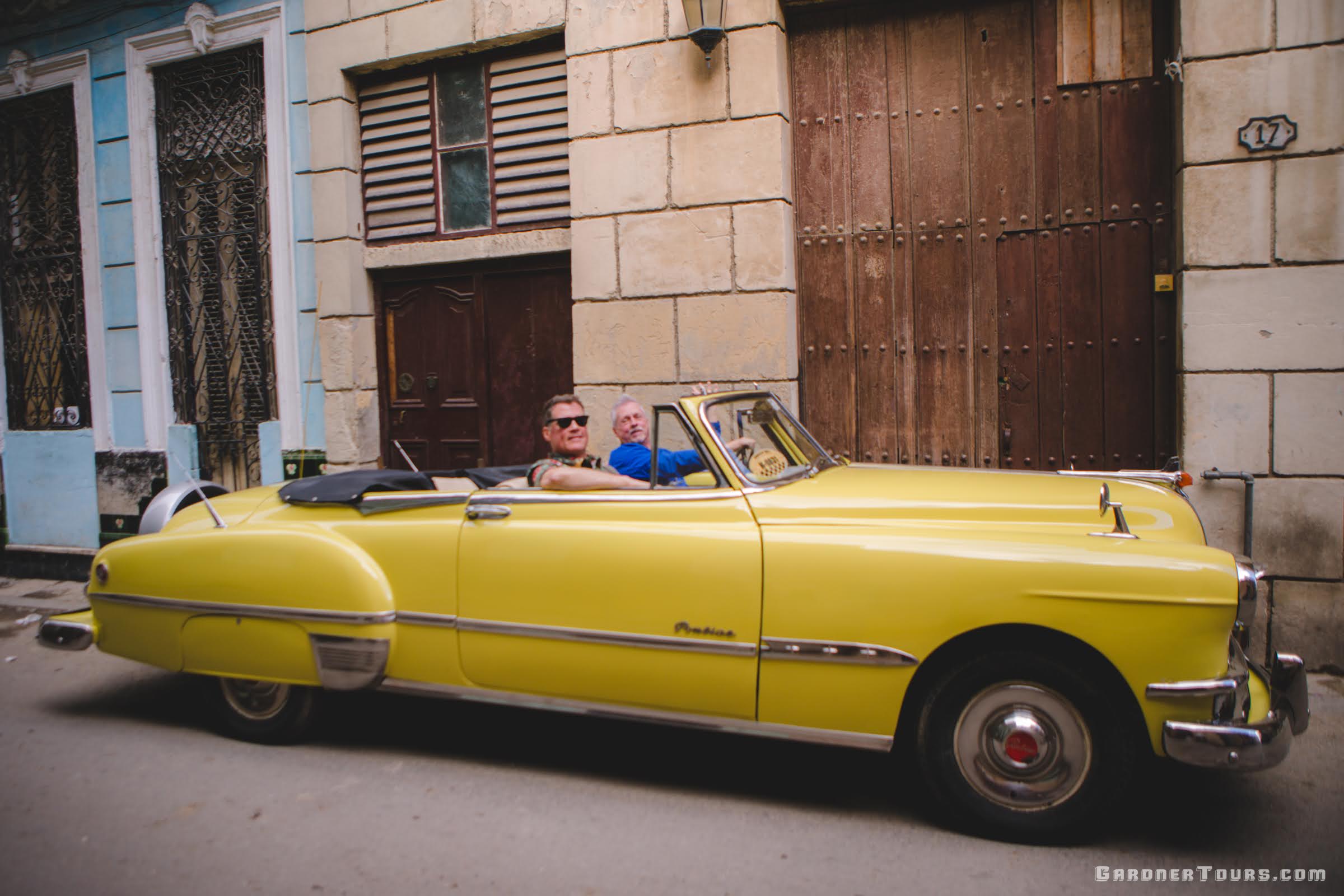 Two men Riding in a Yellow Classic Car (1951 Pontiac Chieftan) in Havana, Cuba