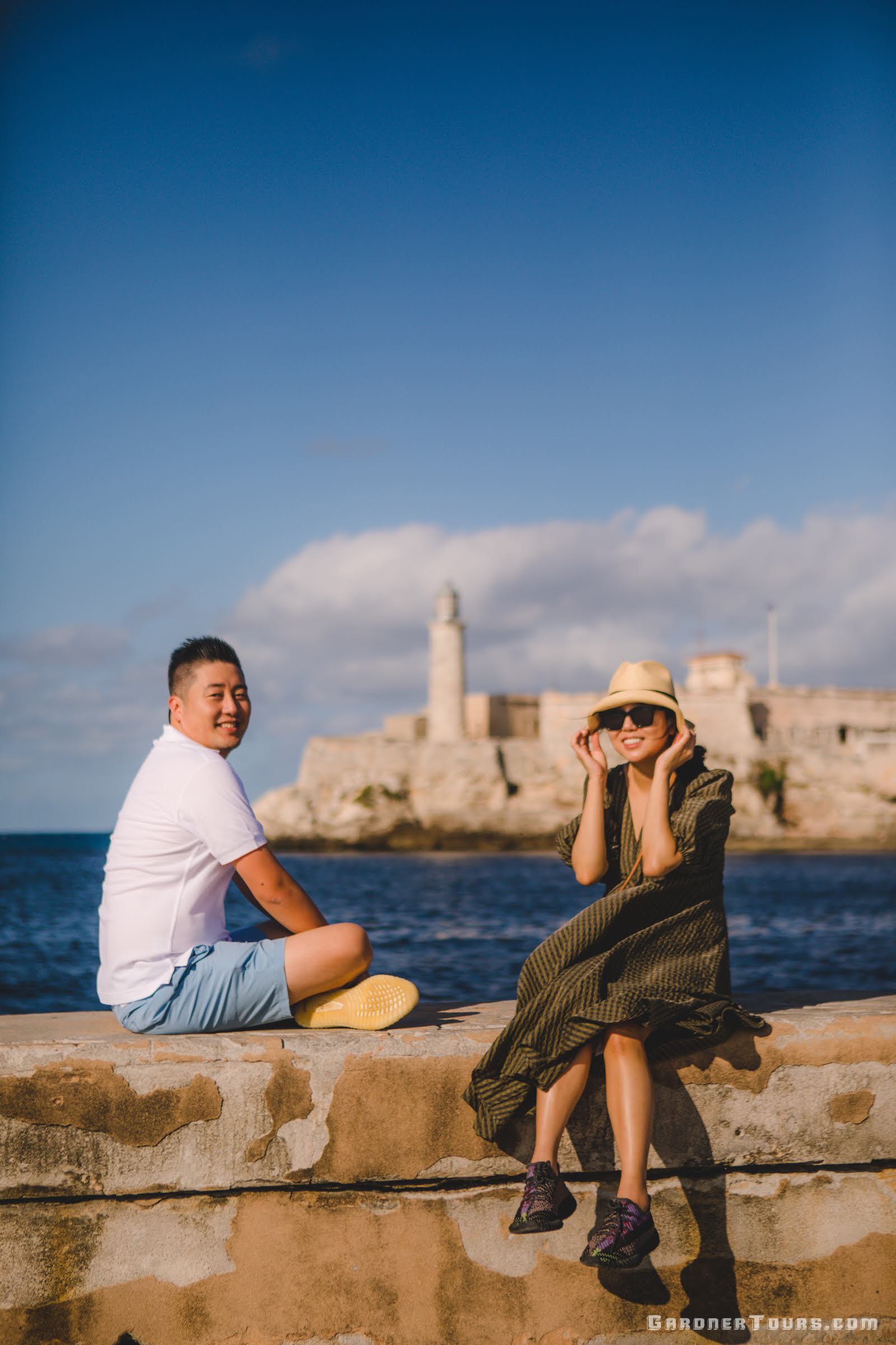 Korean Couple Sitting on the Malecon in front of El Morro Castle in Havana, Cuba